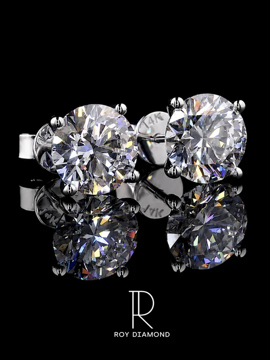 Round diamond stud earrings on a black reflective background