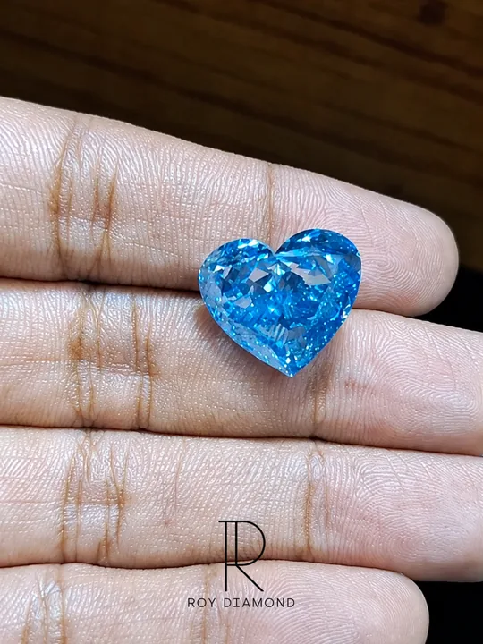 Bright blue heart-shaped diamond displayed on fingers